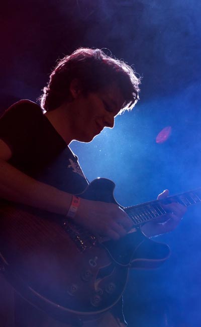 Portrait eines Gitarrenspielers im gedämpften Konzertlicht
